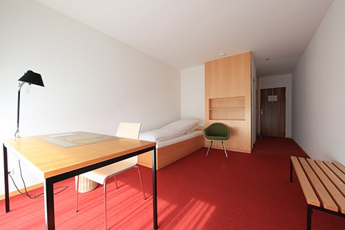 Guest room with beed, desktop, chair, cupboard and bench