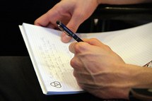 Hands writing on piece of paper